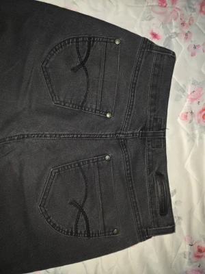 Svarta Replay straight jeans - Säljer ett par svarta jeans från jeans by bessis med klassisk femficksdesign och raka ben. Jeansen har snygga detaljer på bakfickorna och metallnitar. Materialet är slitstarkt jeans och passformen är normal med midwaist. Perfekt för dig som gillar stilrena och tidlösa jeans.