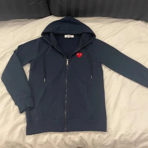 Comme des Garçons Zip-hoodie - Säljer denna full-zip hoodien från Cdg. | Skicka är så gott som nytt. | Den är i en mörkblå/marinblå färg men en röd logga. | Det är bara att höra av sig om man har några frågor eller funderingar kring hoodien⭐️⭐️⭐️