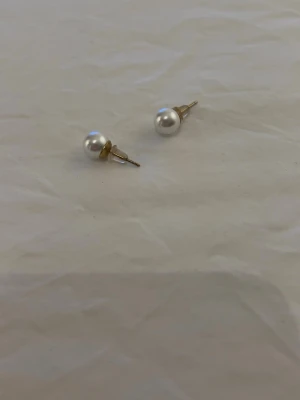 Örhängen från Edblad - Bilderna visar ett par pärlörhängen med guldfärgade detaljer, ingen väst finns med.