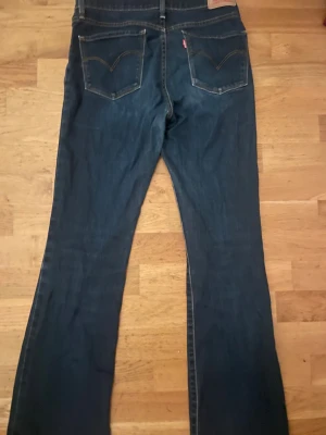Levi's mörkblå bootcut jeans - Säljer ett par klassiska Levi's 315 jeans i mörkblå tvätt med bootcut-snitt. Jeansen har fem fickor, synliga sömmar och är tillverkade i slitstarkt denim. Passar dig som gillar en tidlös look med lite vidare ben. Levi's-märke på bakfickan och röd etikett.