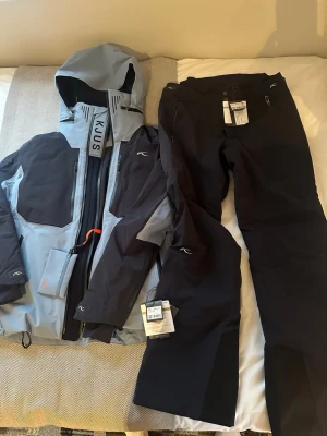 Lasse Kjus skidställ - KJUS herr skidställ – jacka & byxor (nytt med taggar)  Exklusivt skidställ från KJUS, känt för sin höga kvalitet, funktion och stil. Setet består av Men Ligety Jacket och Men Formula Pants, perfekt för alpint åkning i alla väder.  Jacka Modell: Men Ligety Jacket Färg: Blå/grå Storlek: 50 Vindtät, vattentät och mycket andningsbar Avancerad konstruktion för maximal rörelsefrihet Flera funktionella fickor Hög krage och huva för extra skydd Ny med originaltaggar  Byxor Modell: Men Formula Pants Färg