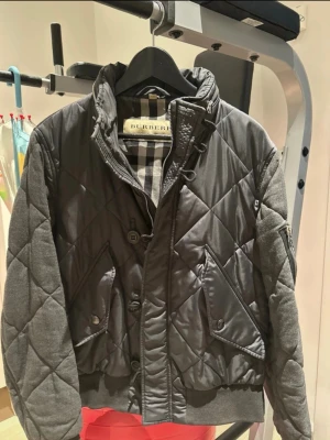 Grå quiltad vinterjacka från Burberry - Herrjacka från Burberry med ryggen och täckjacka. Står strl 52 vilket motsvarar M