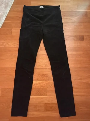 Svarta sammetsbyxor från Filippa K - Säljer ett par svarta sammetsbyxor från Filippa K i storlek medium. Byxorna har en tight passform med hög midja och är tillverkade i mjuk sammet som ger en lyxig känsla. Perfekta för dig som gillar stilrena och bekväma plagg. Mycket sparsamt använda. 