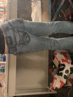 Miss Me ljusblå jeans med broderi - Säljer ett par ljusblå Miss Me jeans med bootcut och snygga kontrastsömmar. Jeansen har broderade bakfickor och två stora svarta kors på framsidan av benen. Modellen är skinny boot och har låg midja. Materialet är klassisk jeans med coola detaljer. Köpa för 1500