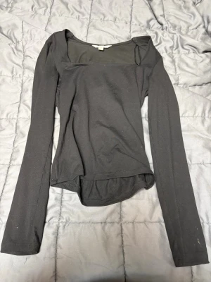 Svart långärmad topp med fyrkantig ringning - Säljer en svart långärmad topp i stretchigt material med snygg fyrkantig ringning. Toppen har en enkel och clean design, storlek XS