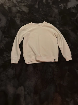 Beige sweatshirt från Kappahl - En stilren beige sweatshirt från Kappahl i mjukt material. Tröjan har rund halsringning, ribbade muddar vid ärmslut och nederkant samt lång ärm. Perfekt för en enkel och clean look.