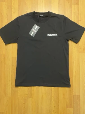 Svart t-shirt med tryck - Svart t-shirt  med vit spegelvänd logga tryckt både fram och bak. Klassisk rund halsringning och korta ärmar. Tillverkad i mjuk bomull för skön känsla och clean look. Perfekt för dig som gillar streetwear och vill sticka ut.