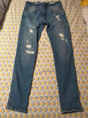 Replay Anbass Slim Fit Jeans Blå 30/32 - Säljer ett par Replay Anbass slim fit jeans i klassisk blå tvätt. Jeansen har slitna detaljer och raka ben, tillverkade i hållbar bomull. Snygg passform med fem fickor och Replay-lapp bak i midjan. Perfekta för dig som gillar en modern och avslappnad look.