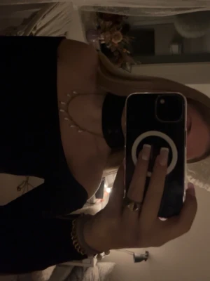 Svart offshoulder topp med choker - Säljer en svart offshoulder topp med långa ärmar och en matchande choker-detalj runt halsen. Toppen har smala axelband och sitter tight över kroppen för en snygg siluett. Perfekt till dig som vill ha en stilren och trendig look.