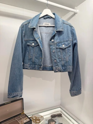 Jeansjacka från Junkyard - Snygg croppad jeansjacka i ljusblå denim från Junkyard. Klassisk design med krage, bröstfickor med knappar och silverfärgade detaljer. 