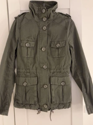 Grön jacka - Jättefin grön jacka som inte kommer till användning då den är för liten. Den har lite lösa sömmar vid armen och en knapp men är ganska enkelt att fixa💕