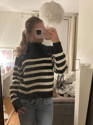 Svartvit randig stickad tröja - Säljer en svart och vit randig stickad tröja med hög hals och långa ärmar. Tröjan har en loose fit och är perfekt att slänga på sig till ett par jeans. Superenkel att styla och riktigt skön att ha på sig. Aldrig använd!🥰