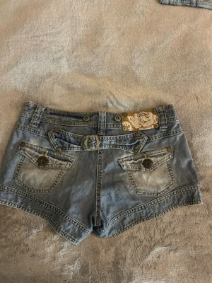 Jeans shorts  - Snygga jeansshorts för flicka i ljusblå tvätt med trendig, sliten look. Shortsen har en bekväm passform och är perfekta för både vardag och sommaraktiviteter.