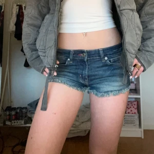 Blå jeansshorts från H&M Divided - Snygga blå jeansshorts från H&M Divided med fransiga kanter. Fina för sommardagar och avslappnade stunder. De har en klassisk femficksdesign och är lågmidjade för en trendig look.