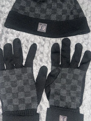  Louis Vuitton mössa/vantar  - Snygg svart mössa och vantar från Louis Vuitton med diskret rutigt mönster och klassisk LV-logga framtill. Pruta går men vid en snabb snabb affär annars nej! 