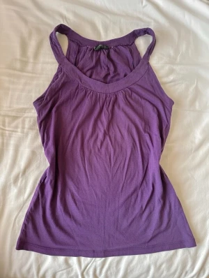 Lila linnetopp  - Säljer en enkel och snygg lila linnetopp från Topshop. Toppen har breda axelband och rundad halsringning. Perfekt till sommaren och lätt att matcha med jeans eller shorts.