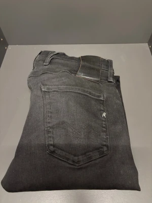 Replay Anbass svarta jeans hyperflex - Säljer ett par Replay Anbass jeans i svart tvätt med klassisk femficksdesign och Replay-logga på bakfickan. Jeansen har slim passform och är tillverkade i mjukt bomullsmaterial med lite stretch. Snyggt slitna detaljer och svart läderpatch i midjan. W29 L32