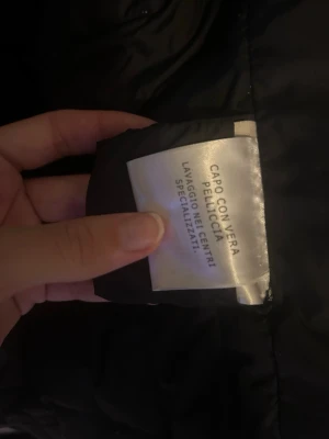 Svart Moncler dunjacka med äkta päls - Säljer en svart dunjacka från Moncler i storlek 4. Jackan har detaljer i äkta päls och klassisk quiltad design. Insidan har Monclers ikoniska serietidningsmärke och logotyp. Perfekt för kalla dagar och riktigt snygg till höst och vinter.