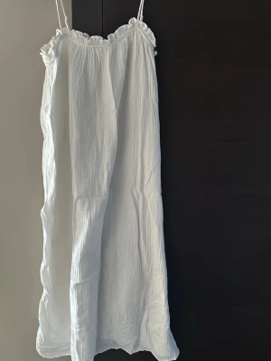 Vit sommarklänning från H&M - Luftig vit klänning från H&M i storlek S. Klänningen har tunna axelband, volangkant upptill och är tillverkad i mjuk bomull. Perfekt för varma dagar och har en avslappnad passform.