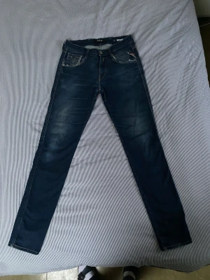 Replay anbass slimfit - Ett par snygga jeans från replay i storlek 30/32. De har några snygga slitningar vid fickorna. Den ena fåglen på bakfickan är lite trasig men det passar in. De är i slimfit så de har en snygg passform.                                        Hör av er vid frågor. 