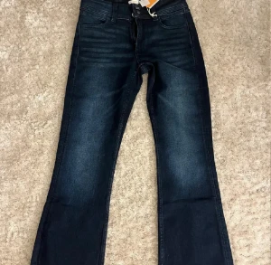 Bootcut jeans från Gina Tricot, mörkblå - Snygga mörkblå bootcut jeans från Gina Tricot i storlek 164. Jeansen har klassisk femficksdesign, broderade bakfickor och midwaist passform. Materialet är jeans med stretch för extra komfort. Perfekt för dig som gillar en tidlös look med lite utsvängda ben. Aldrig använda, sitter bra på mig som bär storlek XS/S. Helt nya!