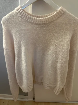 Vit stickad tröja med rund hals - Mysig vit stickad tröja med rund halsringning och ribbade muddar vid ärmslut och nederkant. Perfekt för lager-på-lager och chill dagar. Enkel och stilren design som passar till det mesta.