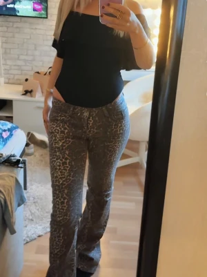 Leopardmönstrade bootcut jeans - Säljer ett par snygga bootcut jeans med leopardmönster i grå och bruna toner. Byxorna har låg midja och klassisk femficksdesign. Perfekta för dig som vill sticka ut med en cool och trendig look.