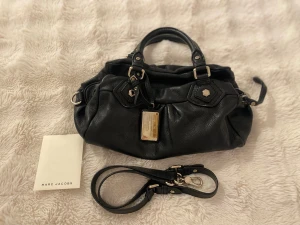 Marc Jacobs svart baby groove mini väska - Svart Marc Jacobs väska i modellen ”baby groove mini” men axelband och dustbag. I mycket bra skick, inga repor eller skador, helt som ny och silver detaljer. Totalt 3 fack inuti väskan. Skriv gärna kring frågor eller fler bilder.❤️