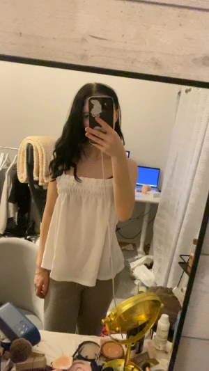 Vit linnetopp från Gina Tricot XXS - Säljer en söt vit linnetopp från Gina Tricot i storlek XXS. Toppen har smala axelband och en rynkad, elastisk kant upptill som ger en chill och luftig vibe. Perfekt för varma dagar och enkel att styla med jeans eller shorts.