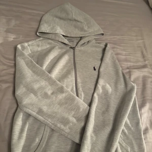 Ljusgrå hoodie från Polo Ralph Lauren - Tja! Säljer en väldigt fin grå Ralph Lauren Zip hoodie i storlek M. Jätteskön och perfekt för vardagen. Kostar nytt över 2000. Tveka inte att höra av er! 🐎