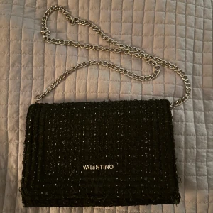 Svart axelväska från Valentino - Jag säljer min Valentino Edamame väska som inte längre kommer till användning. Den är stilren i svart, samt lite glitter, och kedja i silver. Väskan är ganska stor och får därmed plats för ganska mycket vilket är funktionellt. Den har inte använts så mycket är är därför i bra skick! 