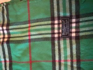 Grön rutig halsduk från Burberrys - Snygg grön halsduk från Burberrys med klassiskt rutigt mönster i svart, vitt och röda detaljer. Gjord i 100% lammull och har fransar i ändarna. Perfekt accessoar för att lyfta din outfit med lite brittisk vibe.