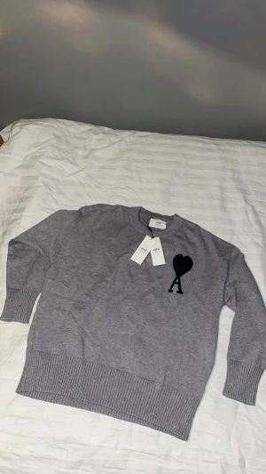  Ami Paris - Tja, säljer en super fin stickad tröja från Ami Paris med svart hjärta och A-logga på bröstet. Perfekt för dig som gillar stilrena detaljer och vill ha en snygg statement piece i garderoben. Hör gärna av dig innan köp! 