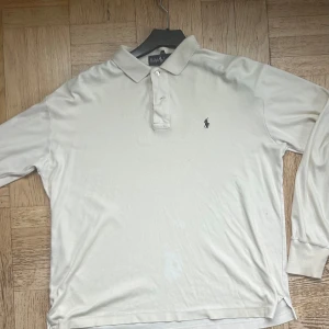 Vit långärmad pikétröja Ralph Lauren - Bra skick, men lite missfärgad på ett ställe som ni ser på bilden, och har krymt till en liten L passar M i tvätten därav det låga priset.