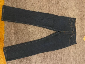 Mörkblå jeans från Nudie Jeans - Snygga mörkblå jeans från Nudie Jeans med klassisk femficksdesign och kontrastsömmar. Jeansen är i modellen Grim Tim och i färgen Dry true navy. Priset går att förhandlas