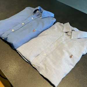 Blå skjortor från Polo Ralph Lauren - Två stilrena blå skjortor från Polo Ralph Lauren. Perfekt för dig som resellar eller bara vill uppgradera din garderob för ett galet bra pris. Båda skjortorna ör i storlek L och är i väldigt bra skick 