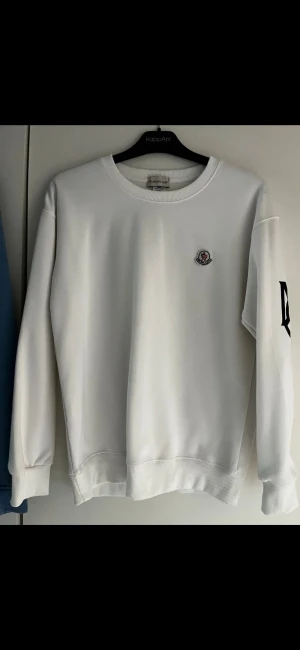 Moncler sweatshirt  - En vit sweatshirt från Moncler, riktigt stilren och fräsch design med loggan på armen. Perfekt till våren eller lager på lager! Storlek S passar mig helt okej som är ca 185.