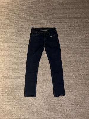 Mörkblå Nudie Jeans  - Snygga mörkblå jeans från Nudie Jeans i modellen Lean Dean. Jeansen har en smalare passform och är smalare än andra jeans i storlek 31. Tillverkade i slitstarkt bomullsmaterialoch är perfekt för dig som gillar en stilren och modern look.