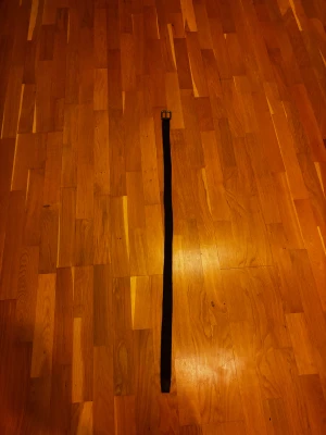 Svart flätat bälte med metallspänne - Svart bälte med flätad design och klassiskt metallspänne i silverfärg. Bältet har detaljer i skinn vid spännet och änden, vilket ger en snygg kontrast. Perfekt för att ge din outfit en clean och stilren touch.