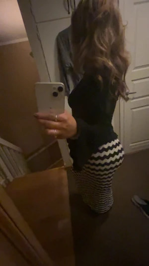 Svartvit långkjol med vågigt mönster - Säljer en långkjol i svart och vitt med coolt vågigt, nästan zigzag-mönster. Kjolen har en figurnära passform och är perfekt för dig som vill sticka ut med en trendig look. Materialet känns mjukt och följsamt, men exakt material är okänt.