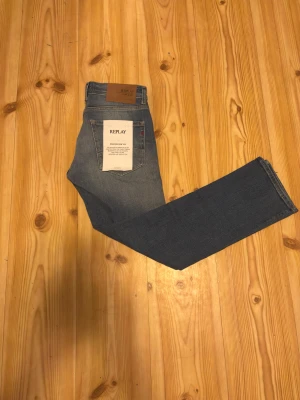 Blå Replay jeans straight fit - Säljer ett par klassiska nya blå jeans från Replay med raka ben och snygg tvätt. Jeansen har fem fickor, normal midja och subtila slitningar framtill för en cool look. Perfekta för dig som gillar en tidlös stil med lite edge.