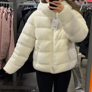 Vit teddyjacka med dragkedja - Säljer en fluffig och mysig vit teddyjacka med huva och dragkedja framtill. Jackan har en söt look med två sidofickor och inbyggda reflexer i fickorna. Perfekt för dig som vill ha en varm och stilren jacka med lite puffig passform. Den är super varm så man fryser inte alls!