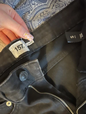 Svarta skinny jeans från 157, stl S, högmidjade  - Svarta skinny jeans från 157 i storlek S. Klassisk femficksmodell med dragkedja och knapp framtill. Snygg passform som sitter tight hela vägen ner och passar perfekt till sneakers eller boots.