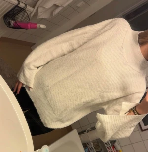 Vit stickad polotröja i loose fit - Säljer en vit stickad polotröja med loose passform och långa ärmar. Tröjan har en hög krage och är ribbad i materialet, vilket ger en snygg och chill look. Perfekt för dig som gillar oversized och vill ha något mjukt och varmt.