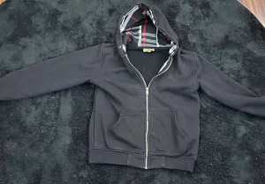 Svart burberry zip - Svart burbery tröja, skick 8/10 har ett liten fläck på högra fickan men går att tvätta bort och den saknar snören. Står storlek M men har krympt i tvätten och passar nu mera XS.