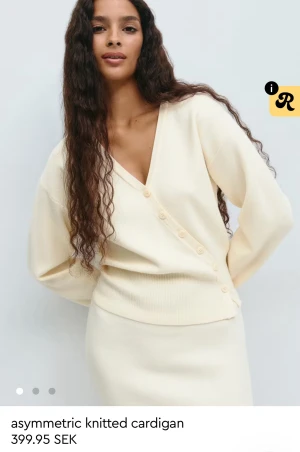 Asymmetrisk kofta från Gina Tricot - Krämvit asymmetrisk kofta från Gina Tricot med v-ringning och knappar snett över framsidan. Tröjan har används endast 1 gång därav priset💗