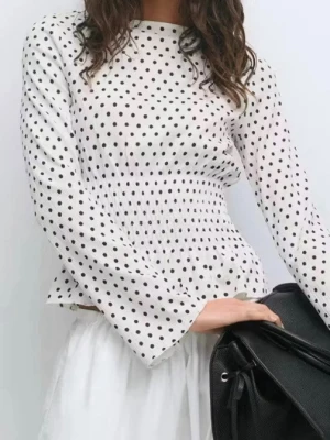Vit prickig blus med smock - Supersöt vit blus med mörkbruna prickar och smockad midja som ger en snygg siluett. Blusen har långa ärmar och lätt volang nertill. Använd en gång.