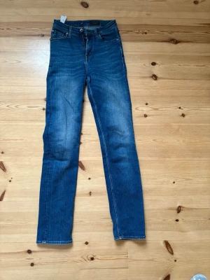 Blå jeans tiger - Säljer ett par klassiska blå jeansbyxor från T/J med raka ben. Storlek 26 midja, 32 längd.