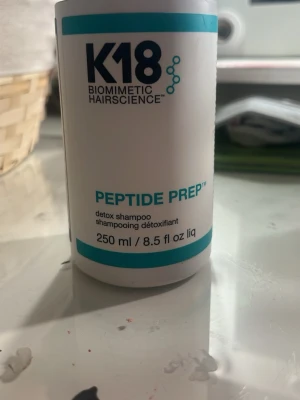 K18 Peptide Prep Detox Shampoo - K18 Peptide Prep Detox Shampoo i en vit och turkos plastflaska på 250 ml. Schampot är utvecklat med biomimetisk hårteknologi och är perfekt för att rengöra och detoxa håret på djupet. Flaskan har en modern design med tydlig logga och text.