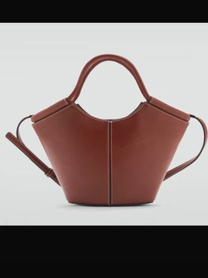 Brun handväska i skinn - Säljer en snygg brun handväska i skinn med unik form och kontrastsömmar. Väskan har ett stadigt handtag och en avtagbar axelrem, perfekt för dig som vill ha både stil och funktion. Enkel men ändå riktigt trendig design.